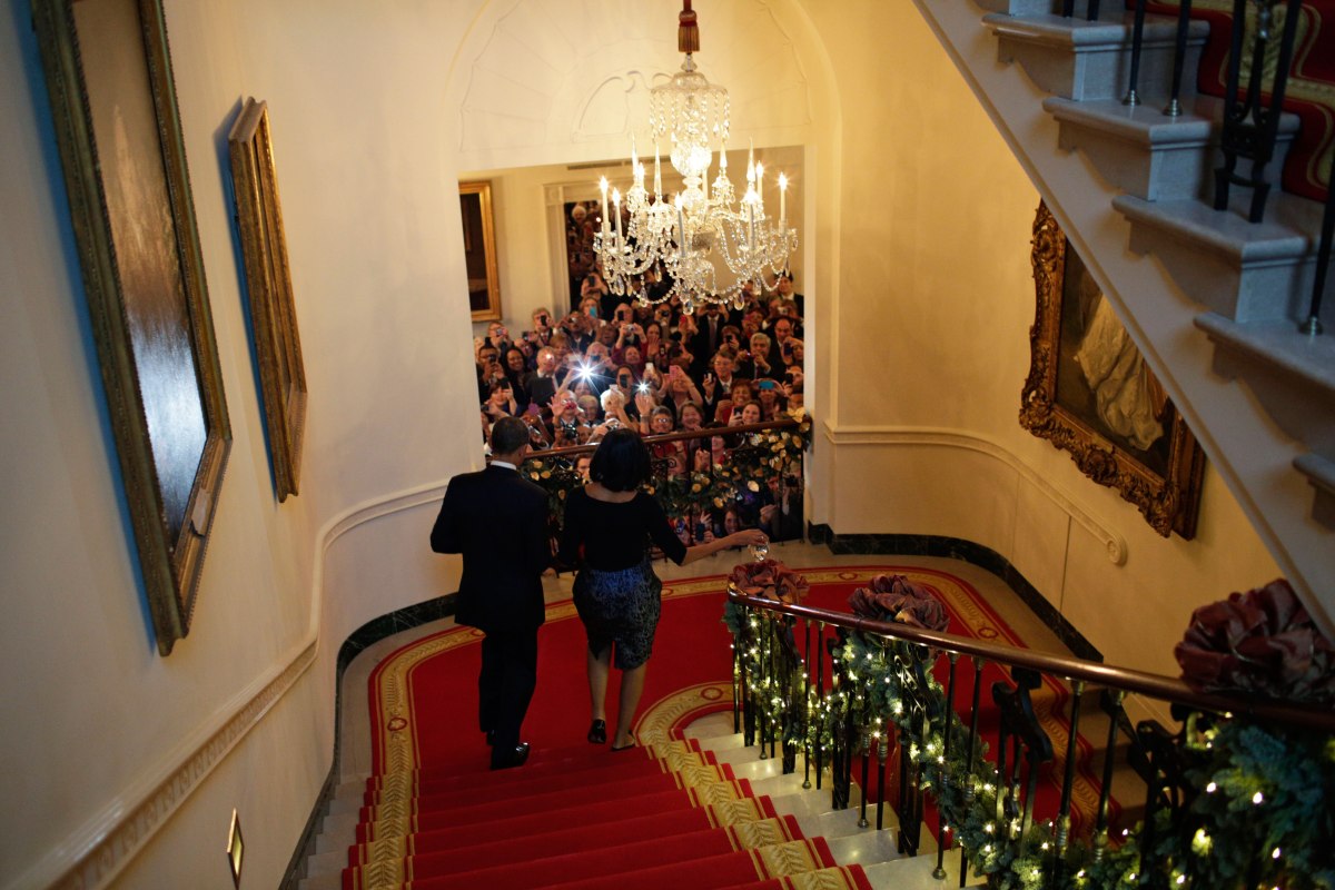 Barack Obama and Michelle Obama descend the White House staircase to a packed audience attending a Christmas Party at the White House, Dec. 12, 2012.