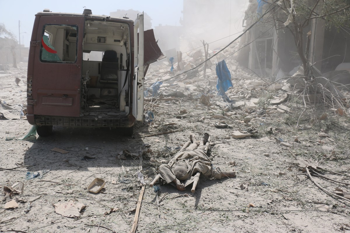 A corpse lies behind a damaged ambulance after regime aircrafts reportedly dropped barrel bombs in the Maadi district of Aleppo on Aug. 27, 2016.