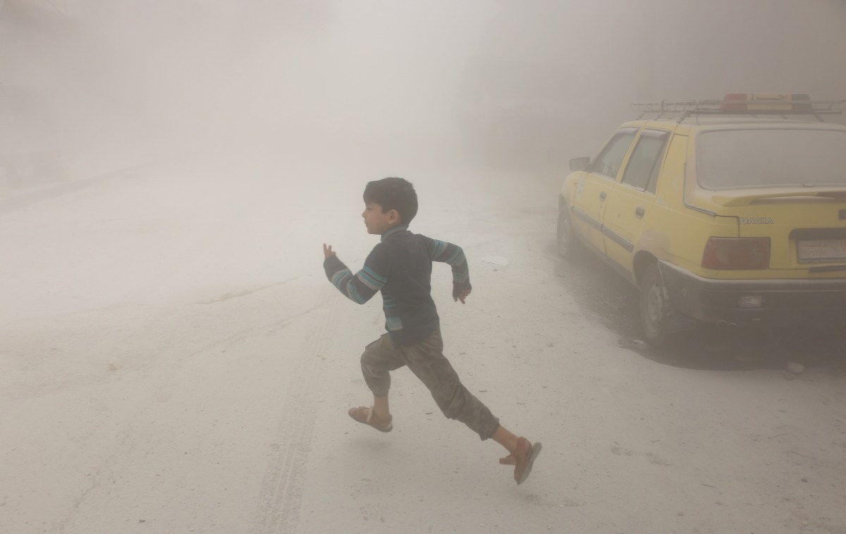 A boy runs after airstrikes conducted by Syrian government forces hit a neighborhood in rebel-held Aleppo on April 24, 2016.