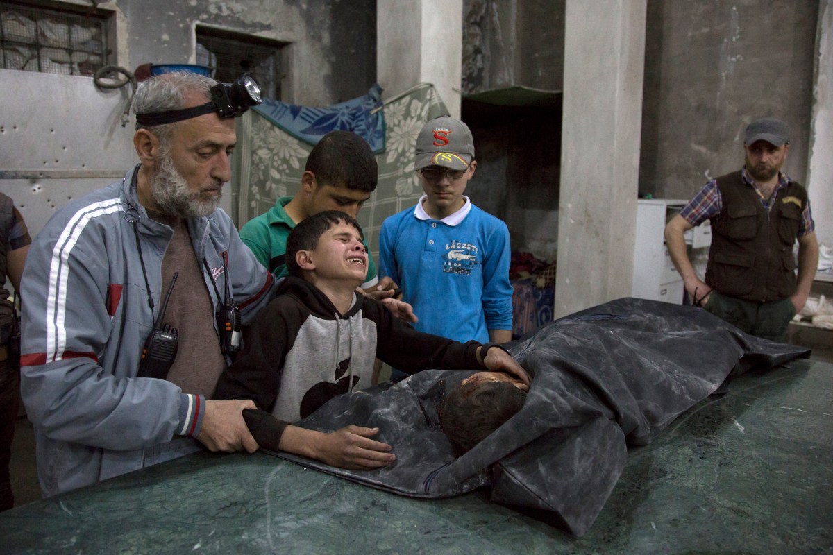 A boy is comforted as he cries next to the body of a relative who died in a reported airstrike in a rebel-held neighborhood of Aleppo on April 27, 2016.