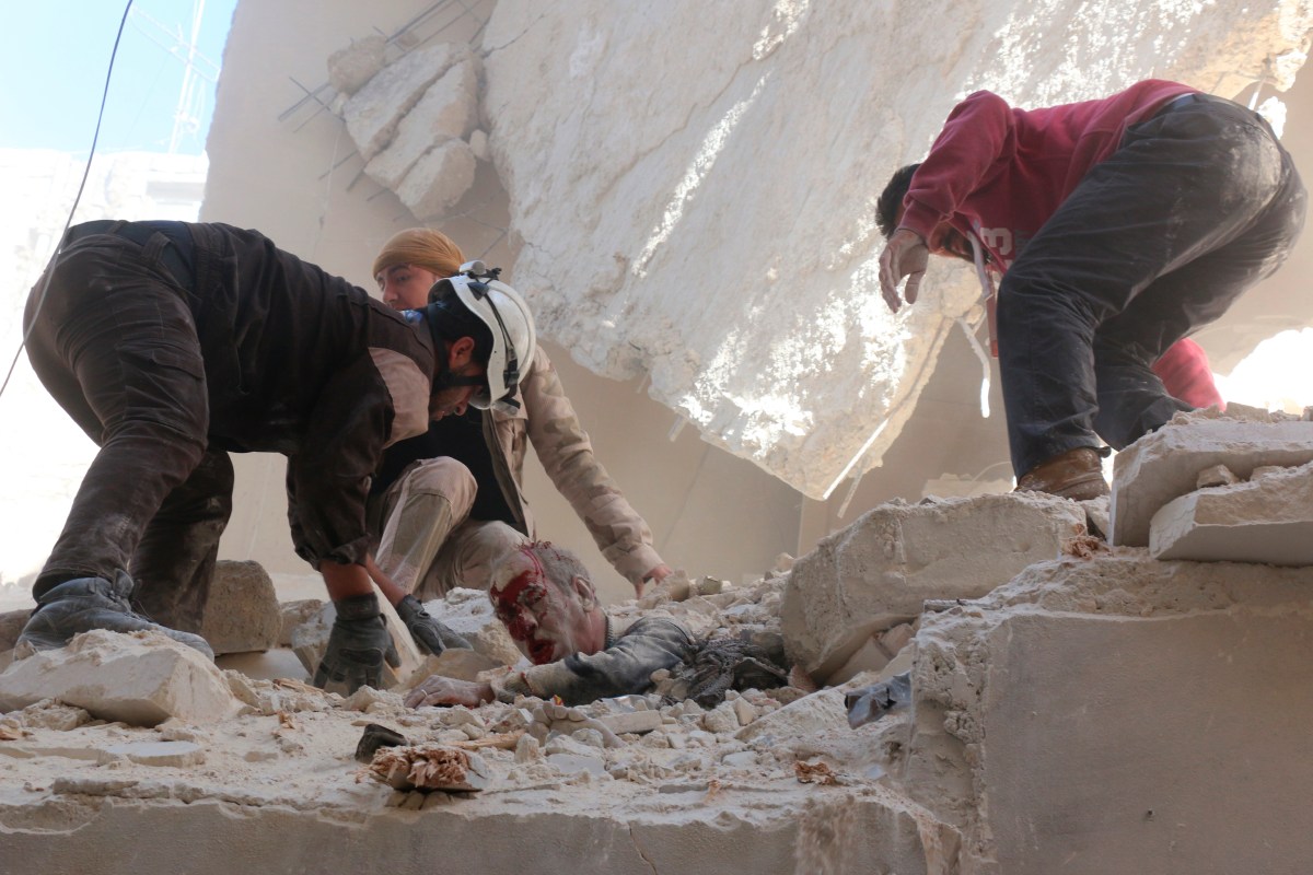 Rescue workers and residents try to pull a man out from under the rubble of a building following a reported airstrike on the rebel-held neighborhood of Salhin in Aleppo on March 11, 2016.