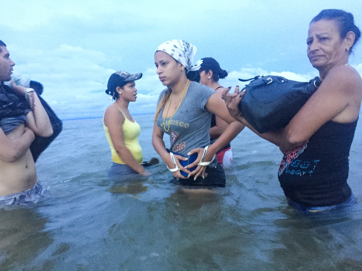 Liset and Marta, with locals who help guide migrants, prepare to board a boat at dawn on June 6, traveling from NecoclÃ­ to CapurganÃ¡, in Colombia, as they close in on Panamaâ€™s border.