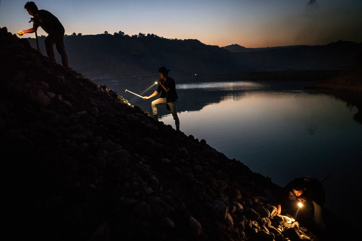 Miners scavenge for jade stones on a slope well after night falls in Hpakant.