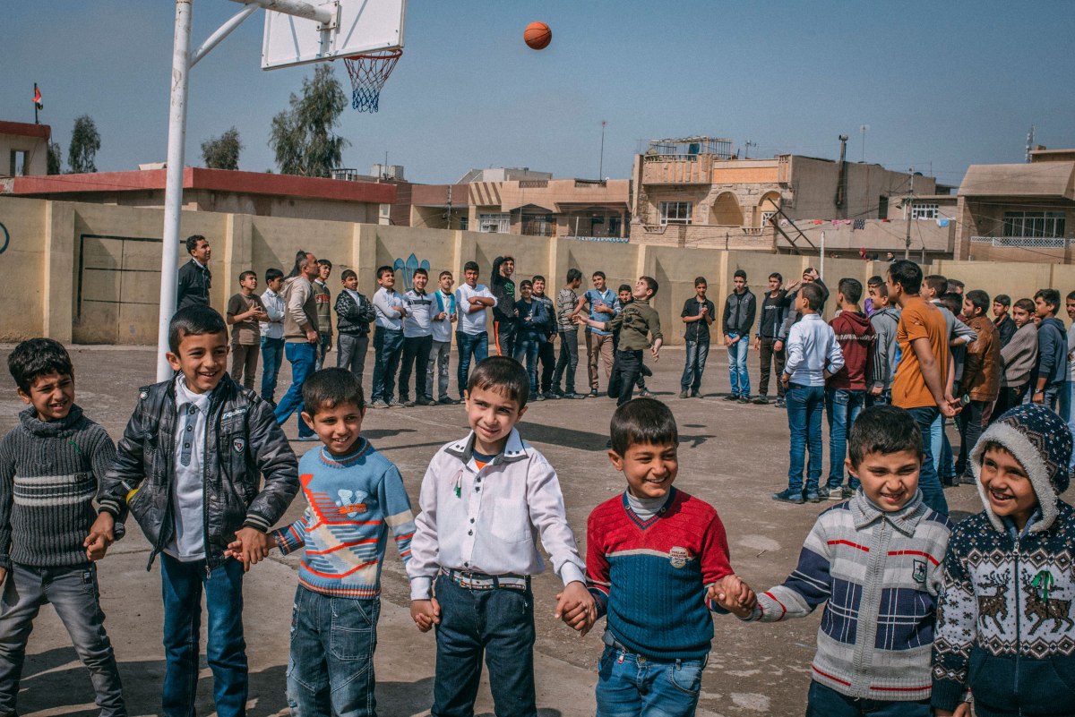 A group of students hold hands while playing in the yard at the Zahret Al-Mada'en school in eastern Mosul on April 2.
