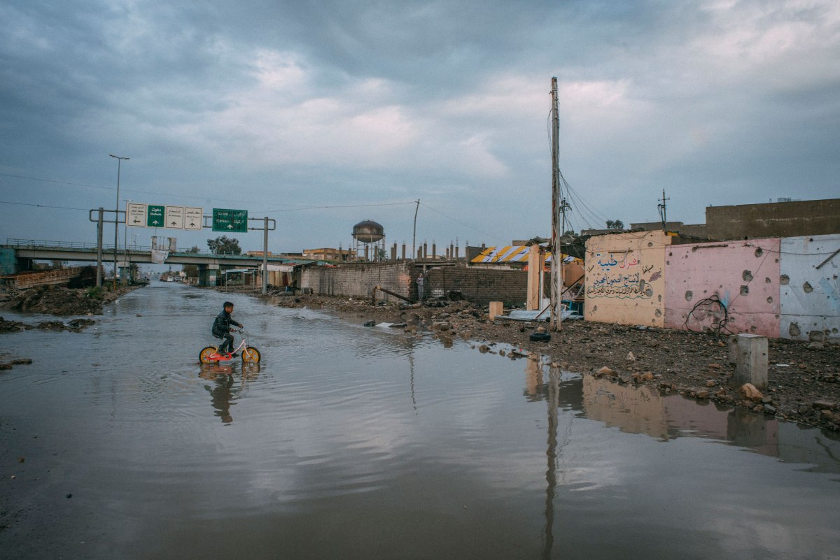 A boy rides a bicycle through floodwaters after heavy rains in the al-Aqeedat district of southwest Mosul on April 1..