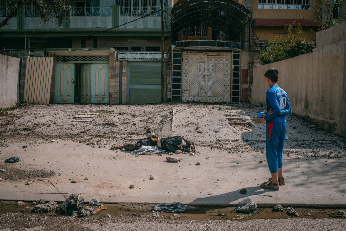 A boy looks at the body of a dead man on the street in the al-Aqeedat district of southwest Mosul on March 29.