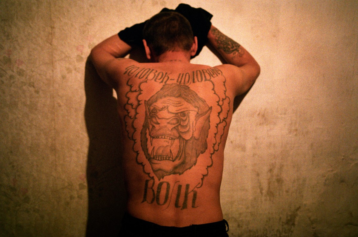 Putin's Russia - The Darkness of Russia 2002 Rybachi village near Vladivostok. Volydya or "Wolf" lives in Rybachi village. The Russian tatoo on his back reads "One man is a wolf to another man." Just after he finished school he went to prison for stealing and was in possesion of a gun and received 2 and a half years. He says he had to steal because his family didn't make enough money. After he got out of prison he wanted to join the army. He longed for a normal life and he knew that without the army he had not chance to stay out of jail. The army commission rejected him with the following explanation "We won't give you a gun so you can rob someone else." He could not find a job and was returned to prison for stealing again. When he got out of prison a local policeman told him "Let us know when you decide to go back to jail, we'll come and drive you there." Stanley Greene—NOOR