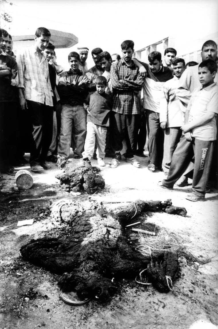 FALLUJAH, IRAQ - MARCH 31: An Iraqi mob gather around a mutilated corpse following an attack on two civilian vehicles on March 31, 2004 in Fallujah, Iraq. Local residents vented their anger by throwing stones at the burning vehicles and dragged out the mutilated bodies. The incident followed an other attack in the town earlier in the day on a U.S. military convoy that killed 5 American soldiers. PHOTOGRAPH BY STANLEY GREENE--AGENCE VU. Stanley Greene—Agence Vu