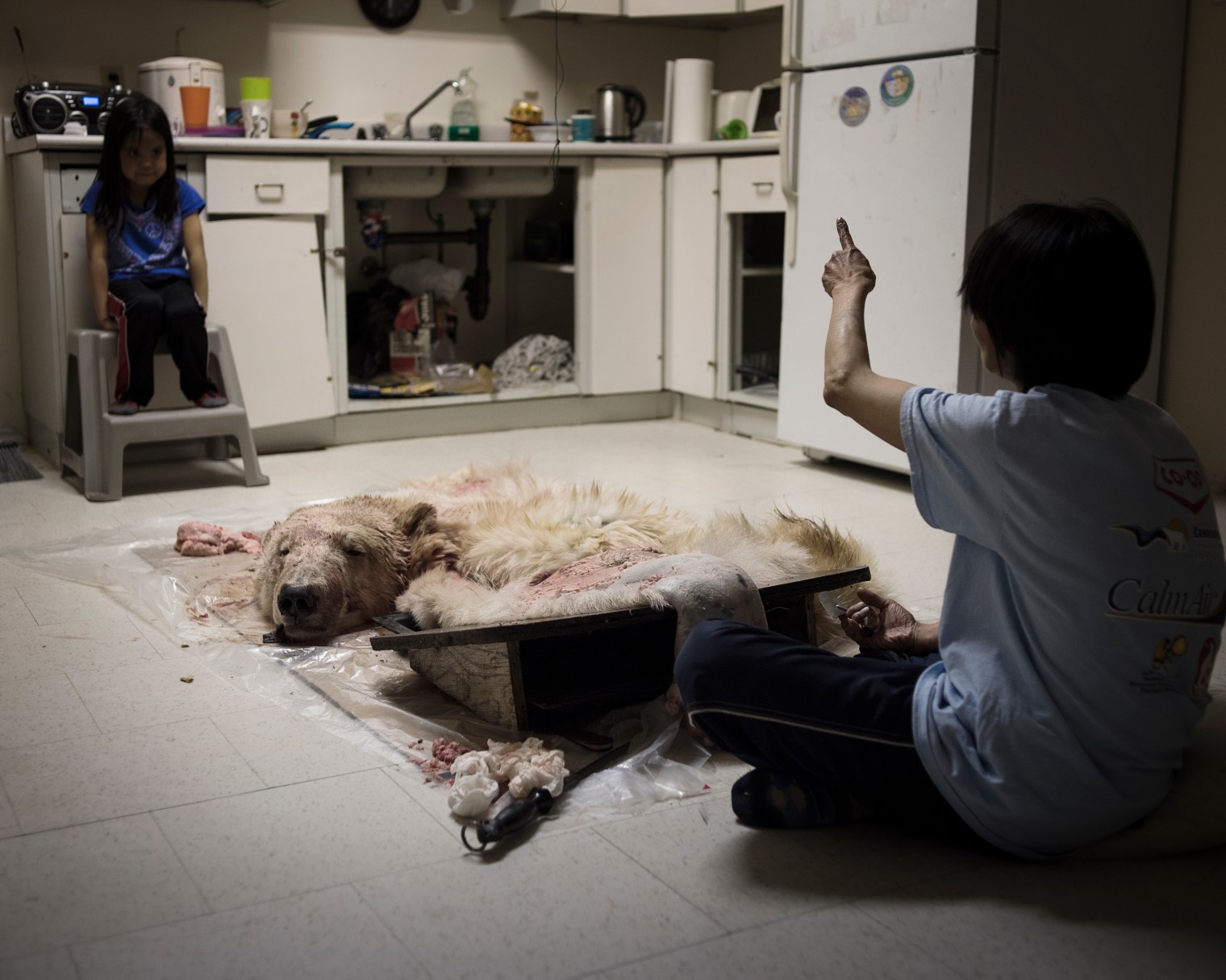 A girl watching her grandmother removing the fat from a polar bear pelt. More than half of the Inuit diet consists of fresh game.