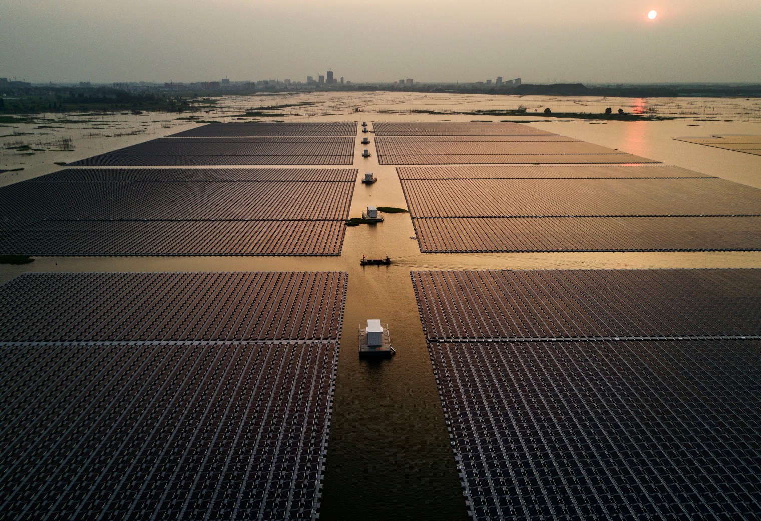Workers ride in a boat through a large floating solar farm project.