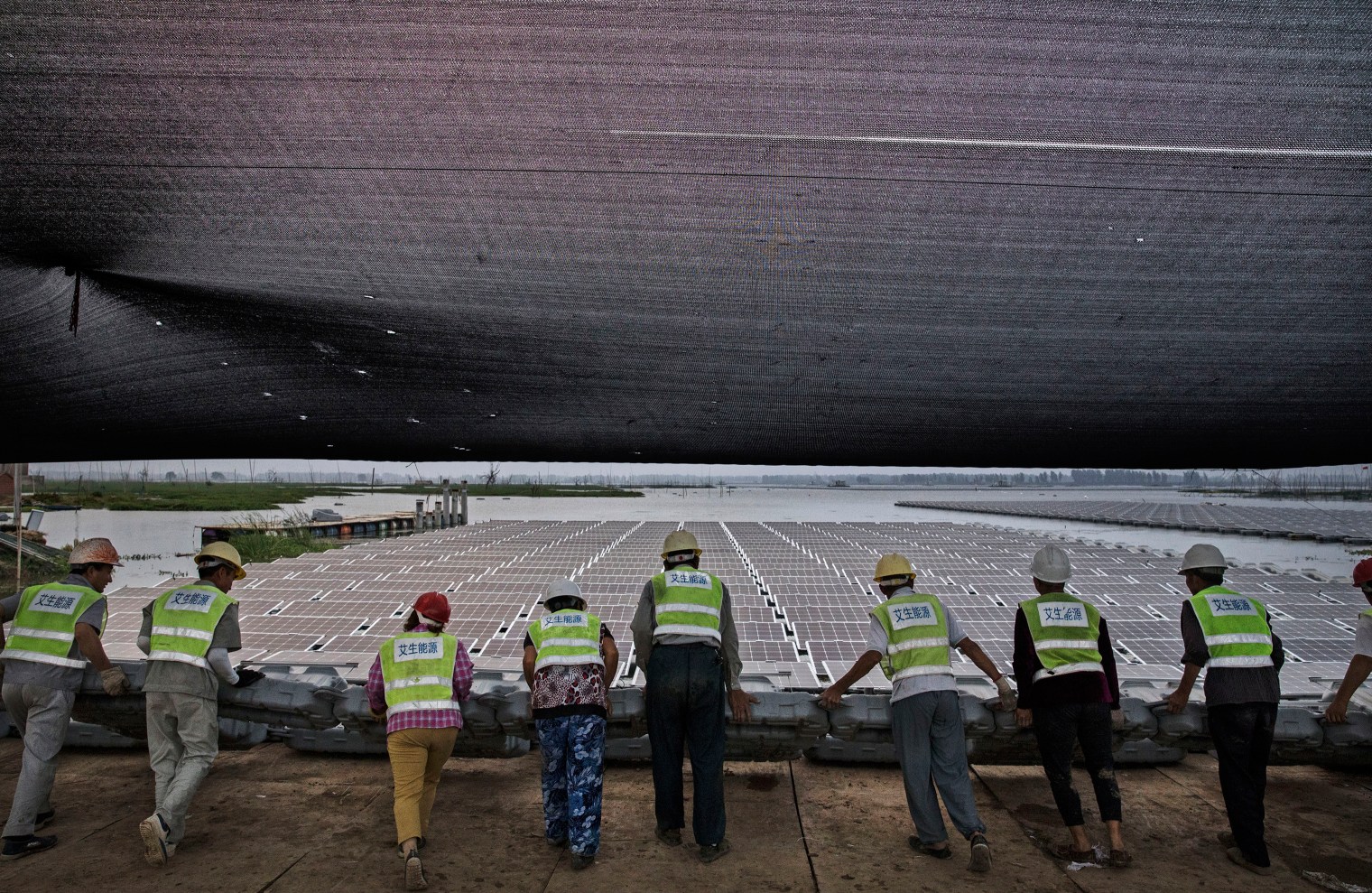 Chinese workers push a section of panels into the water.