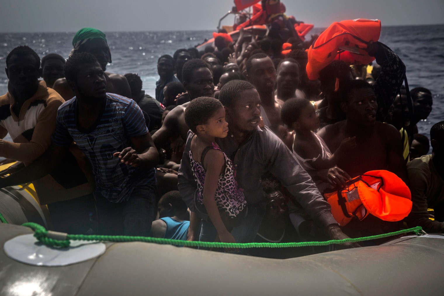 A man and young girl wait to receive life jackets.