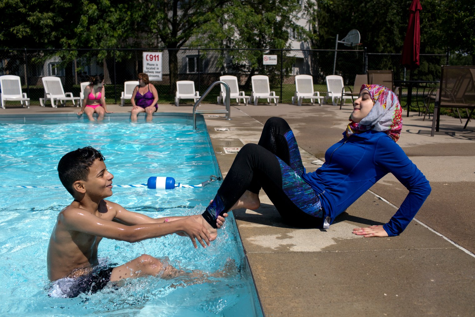 Sedra Tameem pulls away from Taha Albomo Hammed as he tries to pull Sedra into the pool at the Tameem's apartment complex in West Des Moines, Iowa.
