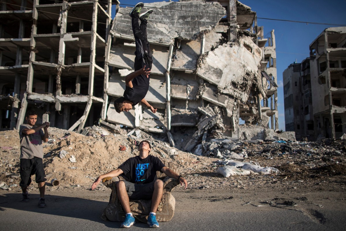 Young men practice parkour among the ruins of buildings that were damaged in the most recent conflict in Gaza, June 30 2015.