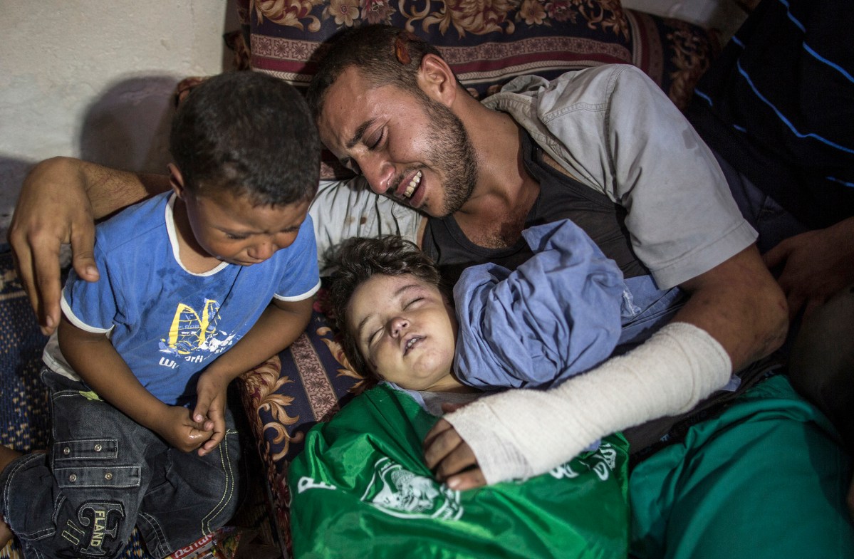 Palestinian father Yehiya Hassan and his son cry over the body of their two years old daughter and sisiter Rahaf Hassan during her funeral in the central Gaza Strip on October 11, 2015. An Israeli airstrike in the northern Gaza Strip killed a Palestinian woman who was five-months pregnant and her 2-year-old daughter. Four other members of the woman's family were injured when their home collapsed in Gaza City's Zaytoon neighbourhood, Gaza Health Ministry spokesman Ashraf al-Qedra said. The Israeli military said it targeted two weapons workshops after Palestinian militants launched a missile at the southern Israeli coastal city of Ashkelon, which was intercepted by the Iron Dome defence system.