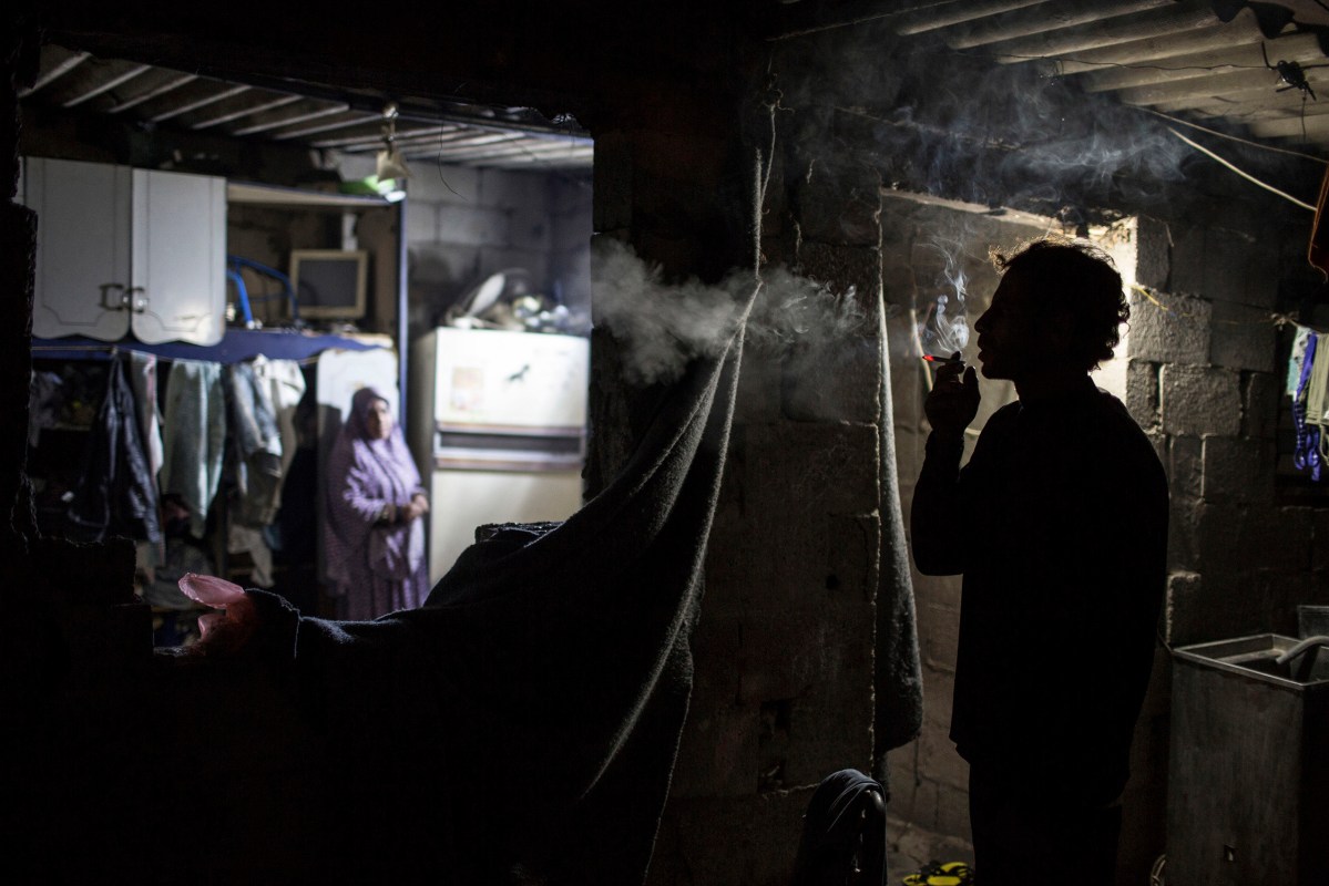 Ahmed Zayara 39, smokes inside his house during cold weather in an impoverished area in Al-Zitun neighborhood in the east of Gaza City, February 4, 2016. 