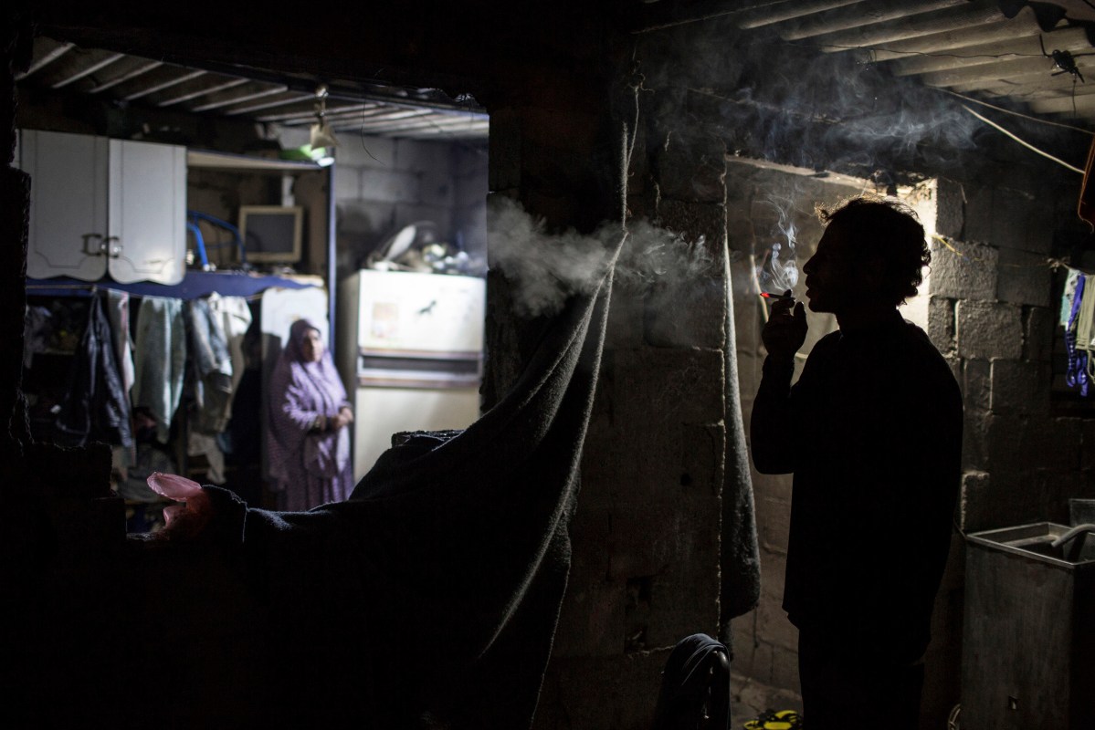 Ahmed Zayara 39, smokes inside his house during cold weather in an impoverished area in Al-Zitun neighborhood in the east of Gaza City, February 4, 2016.