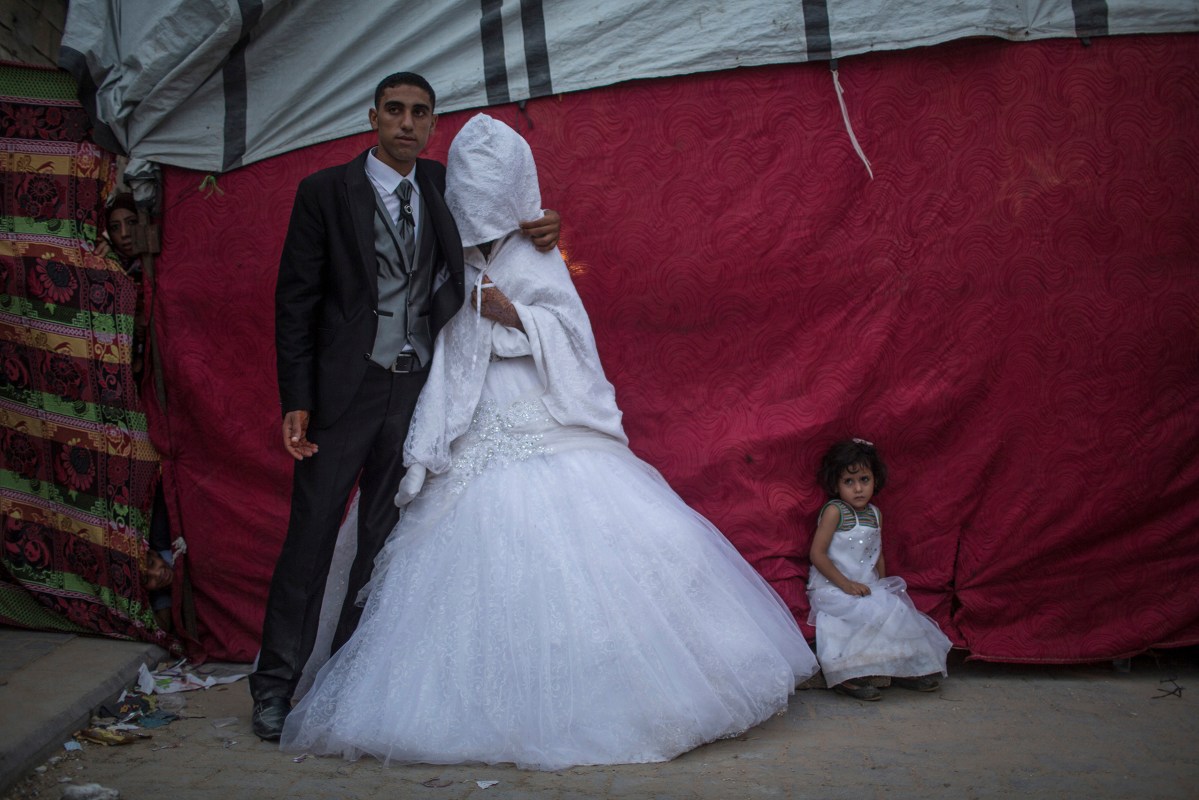 Palestinian groom Mohammed Yousef Al-Masri, 23, and his bride Zekriat Hamza Al-Masri, 20, pose for a picture next to their makeshift tent housing near their destroyed houses, which were damaged during the Israeli war against Gaza in the summer of 2014, during their wedding in Beit Hanun town in the northern Gaza Strip, October 1, 2015.