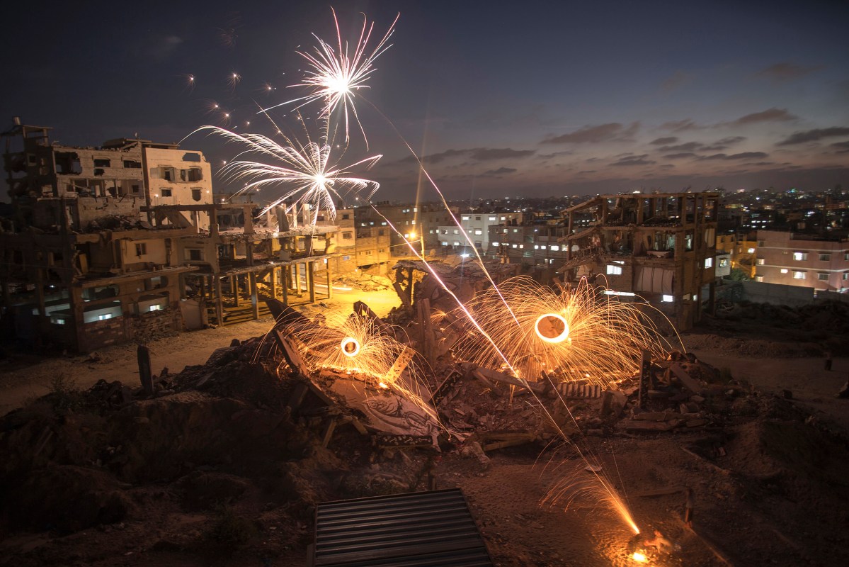 Palestinian young men set fireworks amid the rubble of destroyed houses in Al Shaaf neighborhood, in the east of Gaza City, Gaza Strip, July4, 2015. A group of Palestinians put their aims to light the darkness with fireworks at devastated urban areas in the Gaza Strip during the holy month of Ramadan. They were celebrating the graduation of public secondary students.By Wissam Nassar.