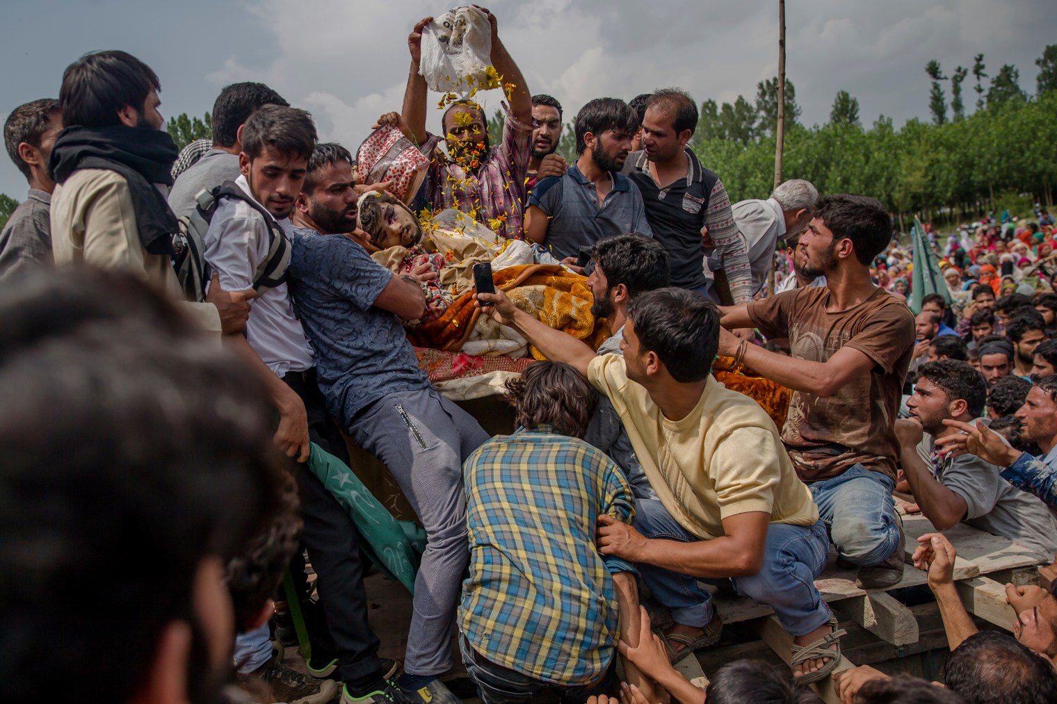 A villager showers flower petals over the body of senior militant Arif Nabi Dar as they display his body during his funeral in Lilhar, about 22 miles (35 km.) south of Srinagar on Aug. 1, 2017.