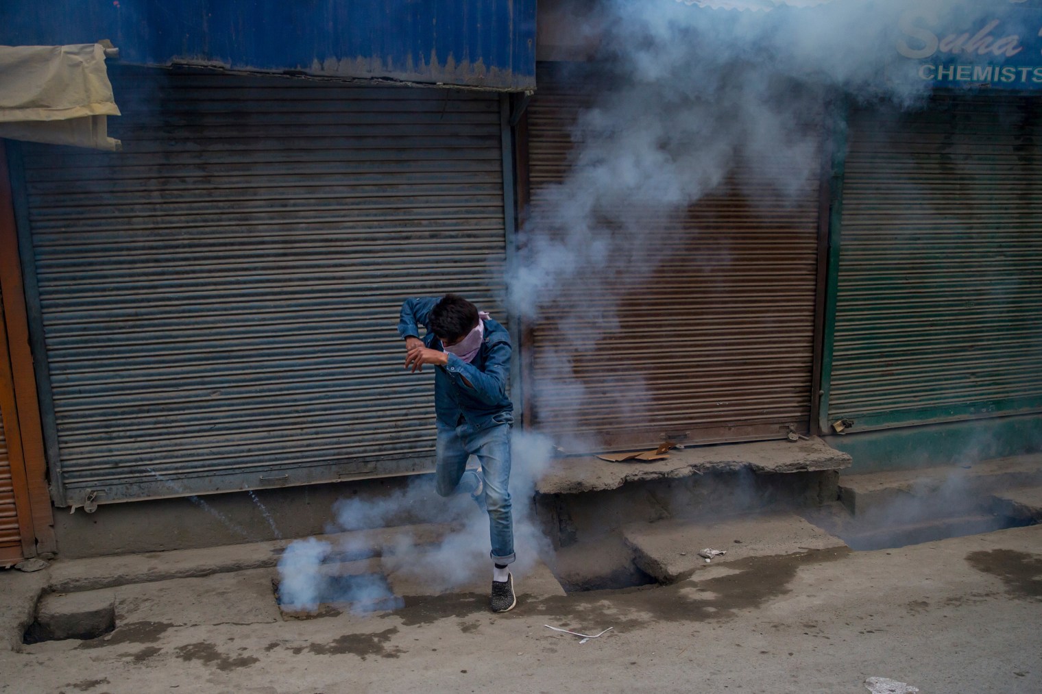 A masked Kashmiri protester jumps to avoid a tear gas shell fired by Indian policemen in Srinagar on May 26, 2017.