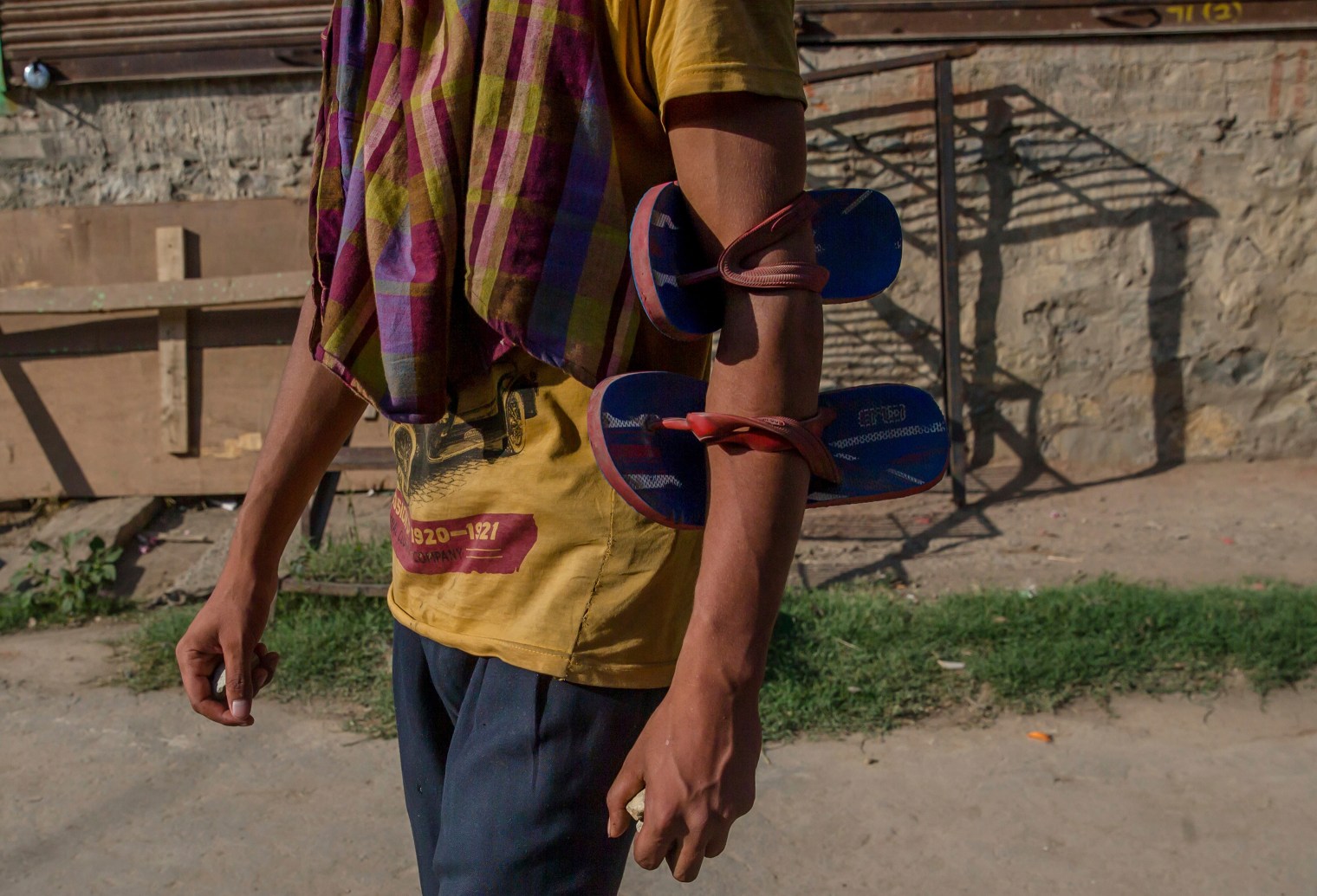 A villager has his slippers tied to his arm as he holds stones before throwing them at Indian policemen to protest during the funeral procession of a civilian Tanveer Ahmed Wani, in Beerwah about 25 miles (40 km.) west of Srinagar on July 21, 2017. The Indian army fired at worshippers outside a mosque in disputed Kashmir on Friday, killing one man and injuring another, after some threw rocks, police and residents said.