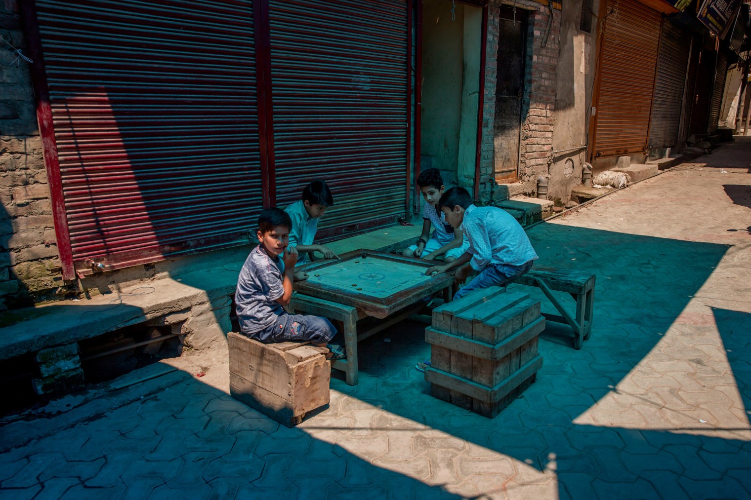 Boys play caromboard on a road outside during a strike in Srinagar on June 9, 2017. Parts of Indian-controlled Kashmir remained under curfew Friday, while general strikes were being staged in other areas after Kashmiri separatists called for strike to protest the Tuesday killing of a civilian by government forces during a search operation to flush out Kashmiri rebels in the southern town of Indian controlled Kashmir.