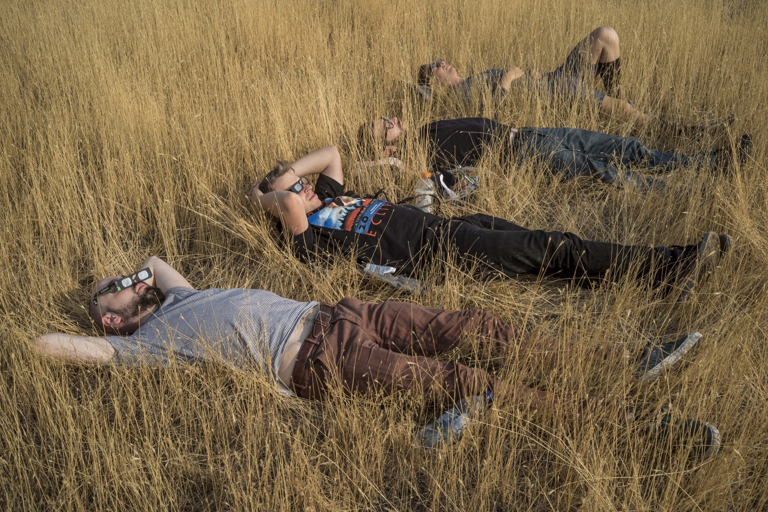 Four men relax before the time the moon will have full coverage over the sun in a field overlooking this small town which is in the path of totality in Madras, Ore., on Aug. 21, 2017.