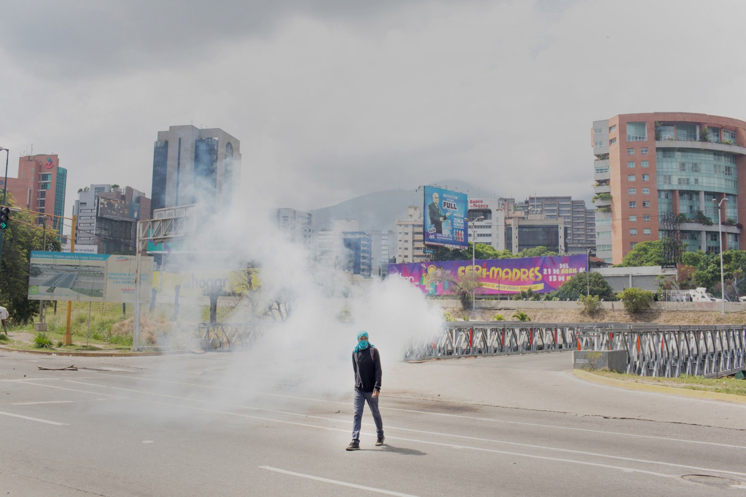 A masked protester walks during a clash with authorities after a silent march honoring the martyrs in Caracas on April 22, 2017.