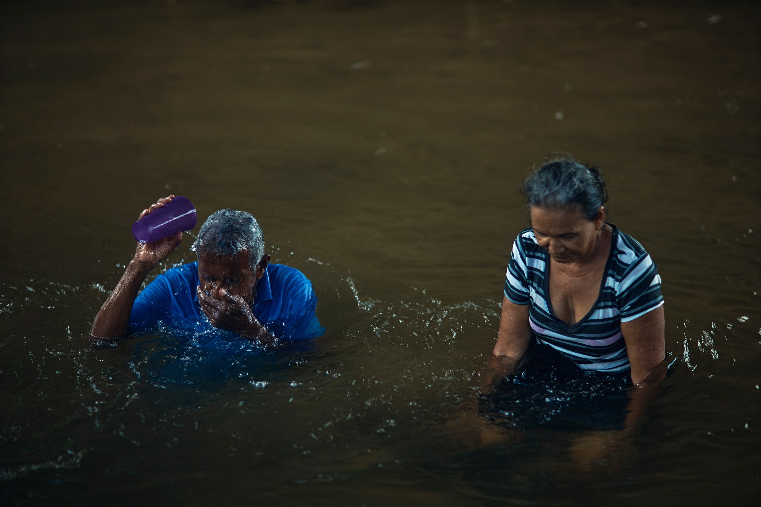 Luis Pinto, 73, and his neighbor Rosa Fernandez, 62, bathe in the river in Juncos, Puerto Rico, on Sept. 29, 2017.