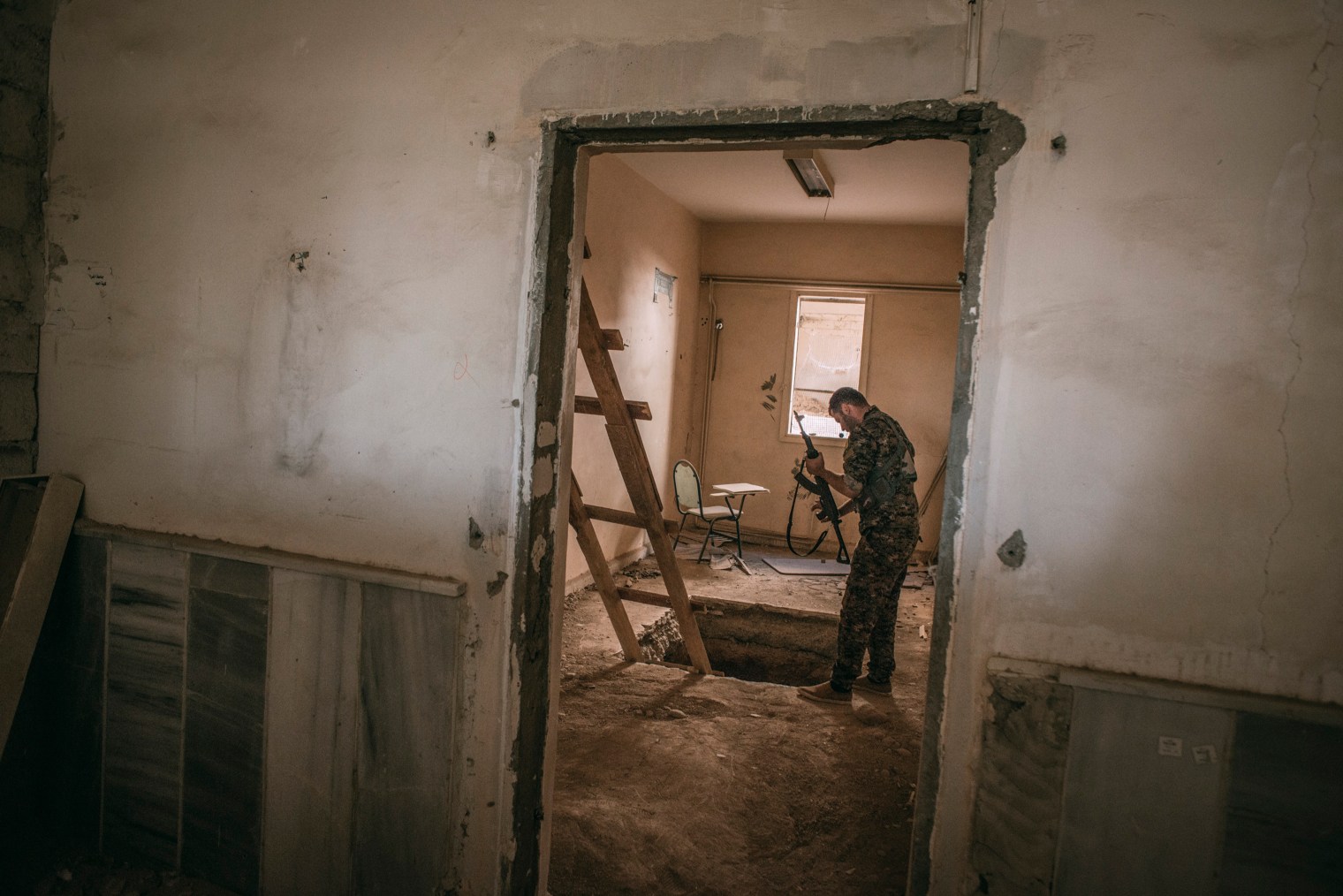 A member of the Syrian Democratic Forces inspects an Islamic State tunnel inside a college in Raqqa on Oct. 18, 2017.