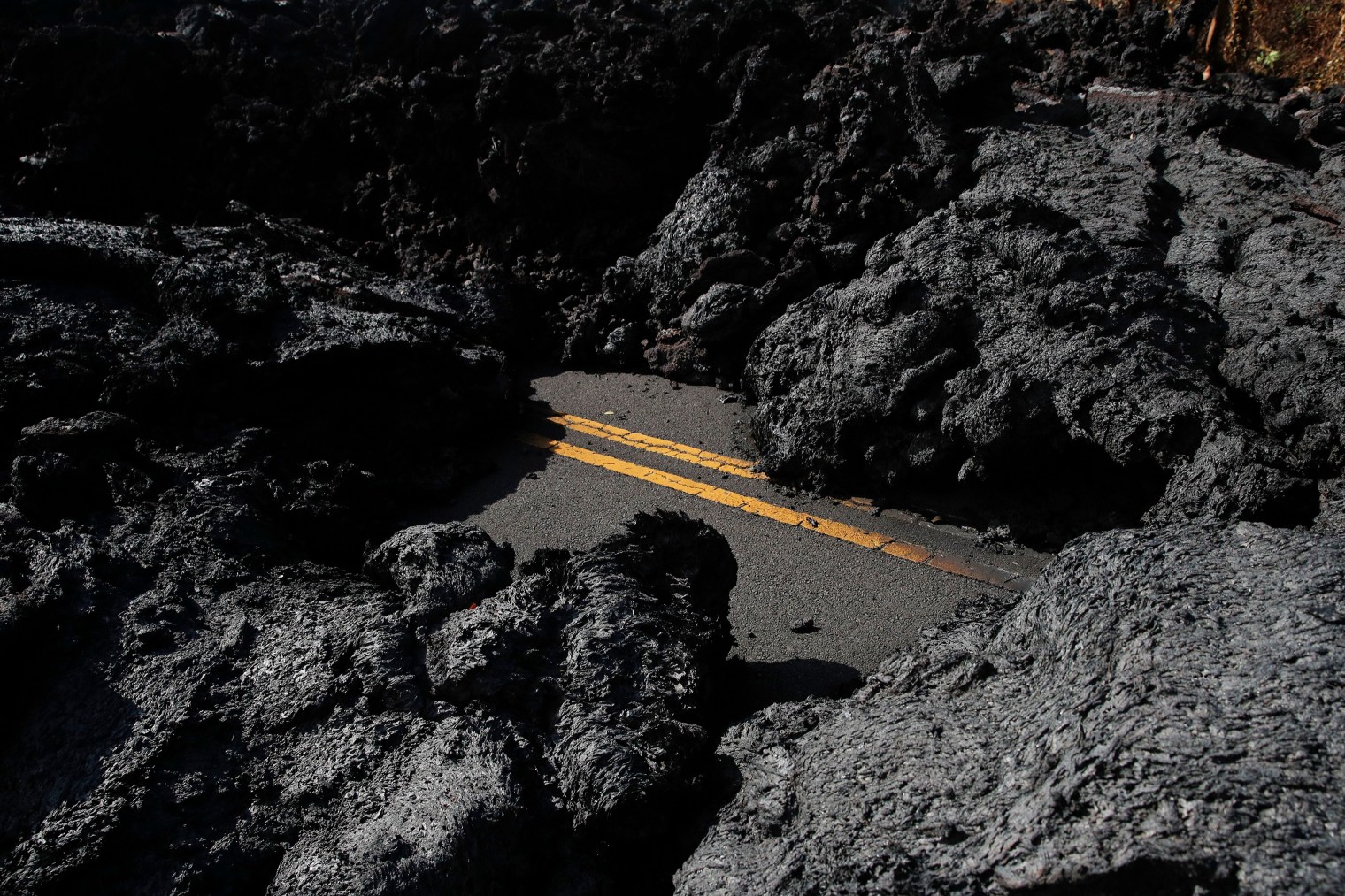 Center lane lines are partially visible along the lava-covered road in the Leilani Estates subdivision near Pahoa, Hawaii, on May 11.